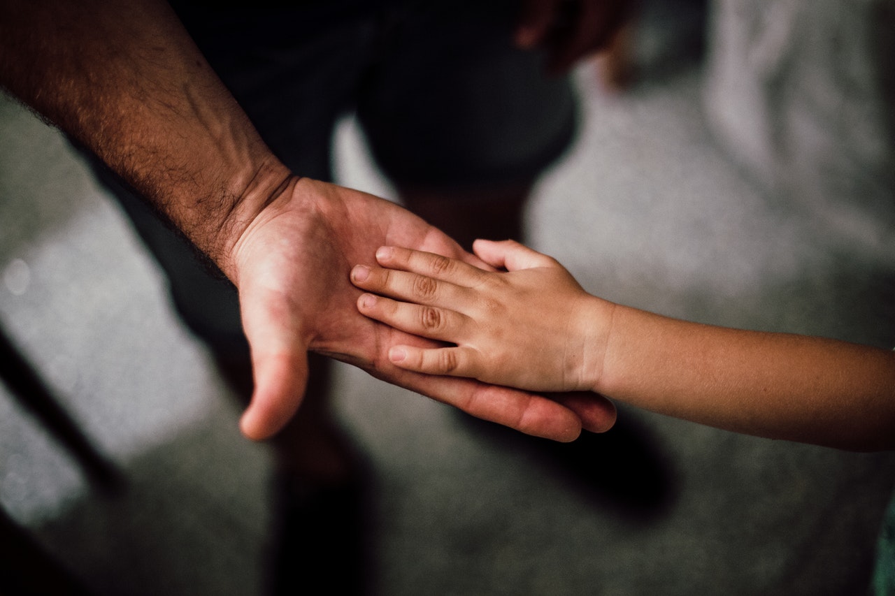 Die Hand eines Kindes ist auf die Hand einer erwachsenden Person gelegt