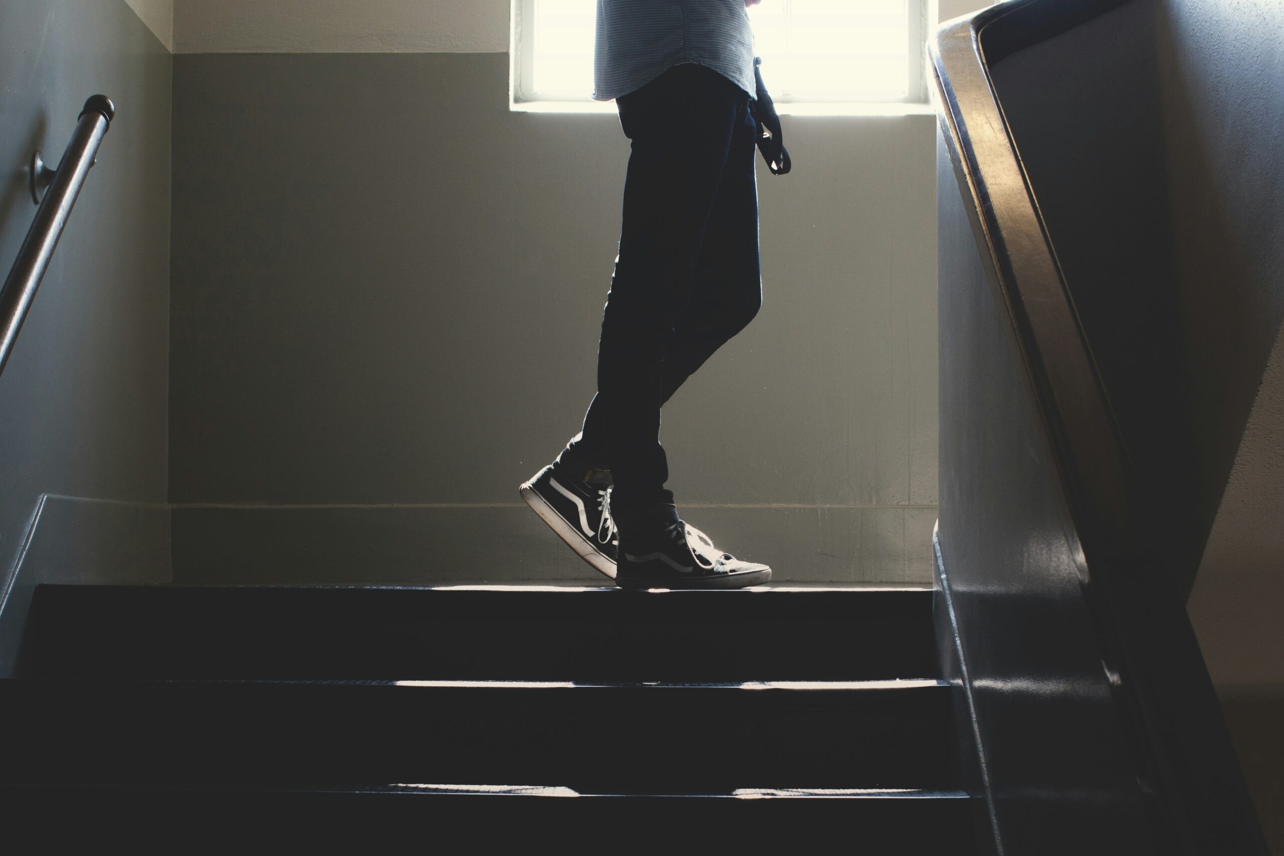 Ein Mensch, dessen Beine man sehen kann, steht oben an einer Treppe.