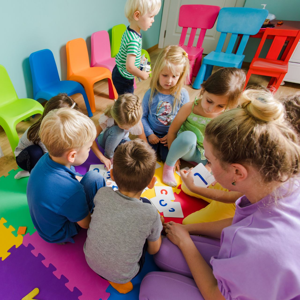 Eine Frau hockt mit einigen Kindern auf dem Boden und spielt